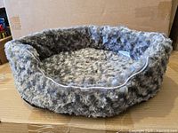 Grey oval plush dog bed showing overall shape and texture