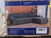 Front of retail insert showing grey L-shaped sofa with slipcover, brand name and product details visible