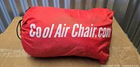Rolled inflatable lounger inside red pouch showing branding
