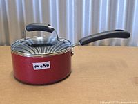 Side view of red non-stick saucepan with lid attached