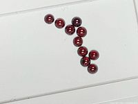 Ten small round red cabochon stones on white surface