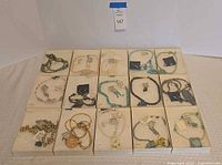 Overview of 16 presentation boxes containing necklaces, bracelets, earrings with tags