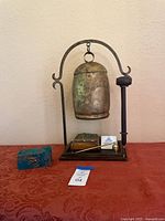 Full view of bronze bell on iron stand with striker, boxes and service bell on base