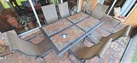 Full view of rectangular patio table with tile top and six matching chairs