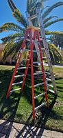 Both ladders standing outside: red 6-ft Werner step ladder in front, silver 16-ft extension ladder behind