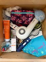 Drawer contents showing Avène products, hair dryer, toothbrush handle, hairbrushes, pouches, cotton balls and face mask