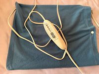 Full view of dark blue electric blanket showing attached beige control cord and snap