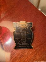 Front of brass advertising clip showing enamel face and text