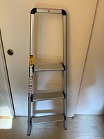 Front view of folded 3-step ladder showing full height and three steps