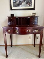 Full front view of mahogany writing desk with upper drawers and gallery