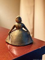 Front view of cast brass lady form bell