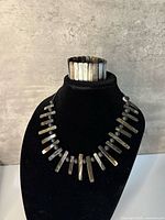 Front view of necklace on bust and bracelet on top showing abalone shell elements