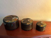 Three lacquer boxes with lids on, showing graduated sizes and decorative tops