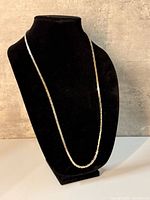 Full view of the flat gold-tone necklace on display bust