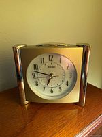 Front view showing Seiko alarm clock face, numerals, hands, and gold/chrome case