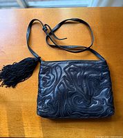 Front view showing abstract leather design, strap, tassel