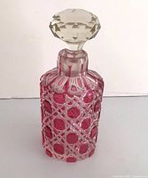 Full view of cranberry cut crystal perfume bottle with stopper attached
