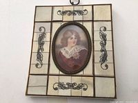 Frontal view of framed miniature portrait showing full frame, portrait, tiles, scrollwork, and hanging ring