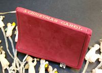 Miniature red leather book with gold spine title surrounded by celluloid angels