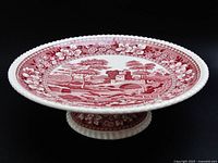 Side perspective of red transferware pedestal cake plate showing pattern and pedestal base