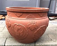 Side view showing embossed bird and leaf motifs on terracotta jardinière