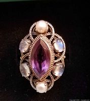 Top view of ring showing marquise amethyst center, pearls top and bottom, moonstones on sides in silver filigree
