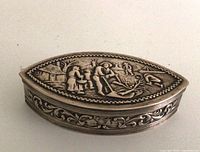 Top view of closed navette-shaped box showing repousse Dutch scene