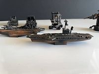 Assorted military die-cast sharpeners and two boats on white surface