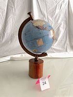 Full view of globe on base showing North Pacific and cylindrical wooden stand