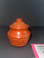 Front view of terracotta jar with lid in place displaying etched band