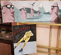 Both artworks hanging; Easter Island above, Superman below