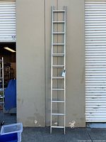 Full view of aluminum extension ladder leaning against wall