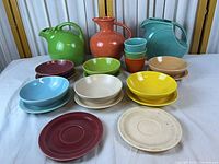 Full lot showing three pitchers, stack of cups, assorted plates and bowls