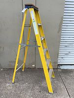Full view of yellow Keller A-frame ladder standing open on pavement