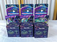 Front view of three Crazy Aaron’s putty packs and three Gear Ball boxes