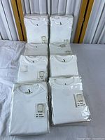 Eight sealed white baby onesie packages arranged on table