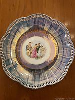 Front of plate showing scalloped pierced rim, luster border and central scene