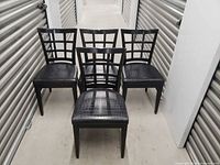 Four black lattice-back dining chairs front view