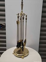 Full view of brass fireplace tool set on stand