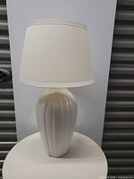 Full view of white ceramic table lamp with shade