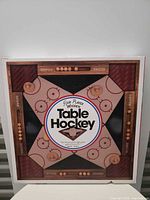 Front of sealed box displaying wooden table hockey board