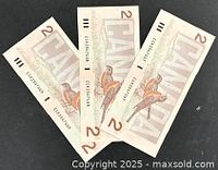 Three $2 Canadian banknotes reverse side with robins