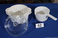 Overall view of casserole with steamer insert, glass lid, and measuring cup