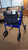 Rear view of blue Hugo Elite walker showing padded backrest, storage bag, wheels