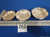 Three sterling silver bowls next to rulers showing diameter and lot tag