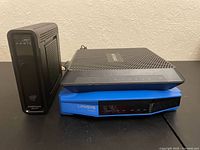 Arris modem-router, Netgear router stacked on blue Linksys router