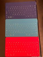 Three colored Bluetooth keyboards stacked