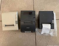 Front view of three Epson receipt printers showing colors and paper feed