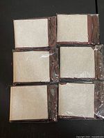 Six sealed brown leather wallets in plastic sleeves