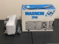 Magnon projector alongside Magnon ZRS box, power cord visible